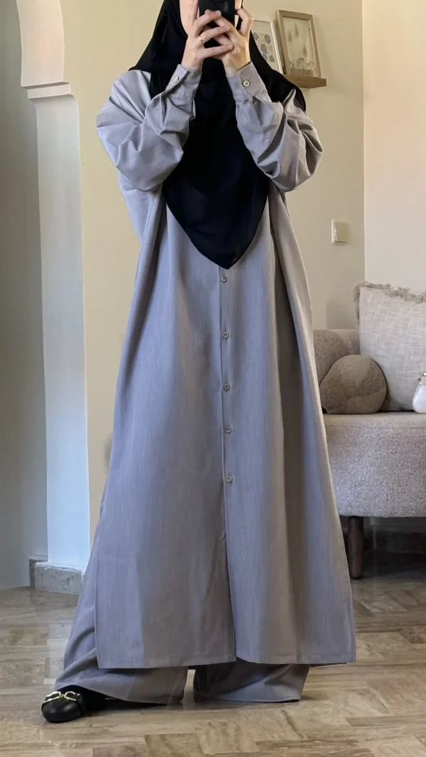 alt="طقم نسائي محتشم باللون الرمادي، قميص بأزرار خشبية وبنطال طويل وواسع مناسب للأجواء الحارة والمعتدلة"